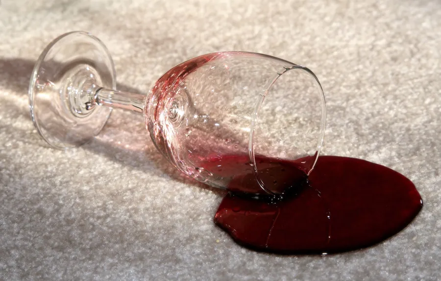 Red wine spilled on a light carpet — the kind of stain Chem-Dry lifts out